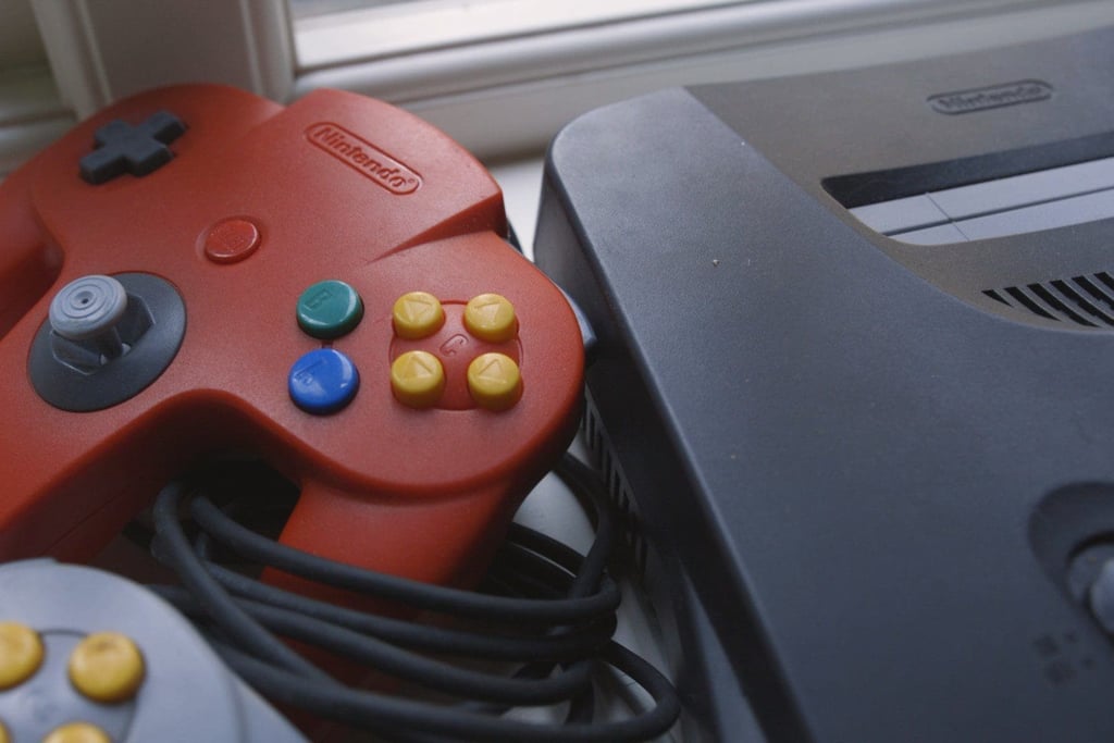 Rød Nintendo 64-kontroller ved siden av konsollen