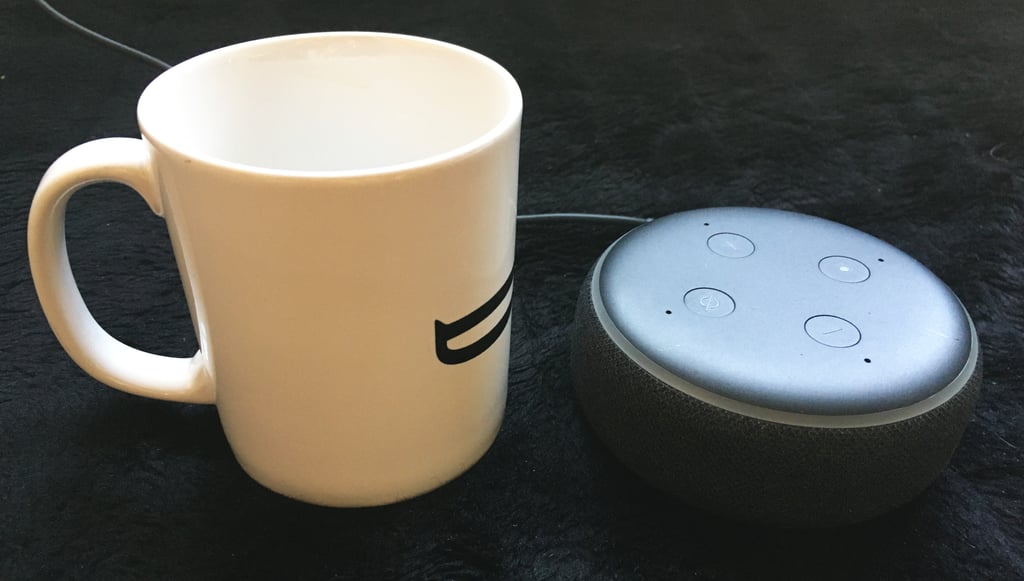 Amazon Echo Dot fotografert ved siden av en vanlig kaffekopp som størrelsessammenligning
