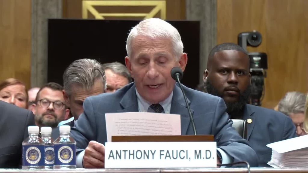 Anthony Fauci sitter ved vitnebordet i en høringssal og leser fra et ark. Foran ham står et navneskilt med teksten ANTHONY FAUCI, M.D.