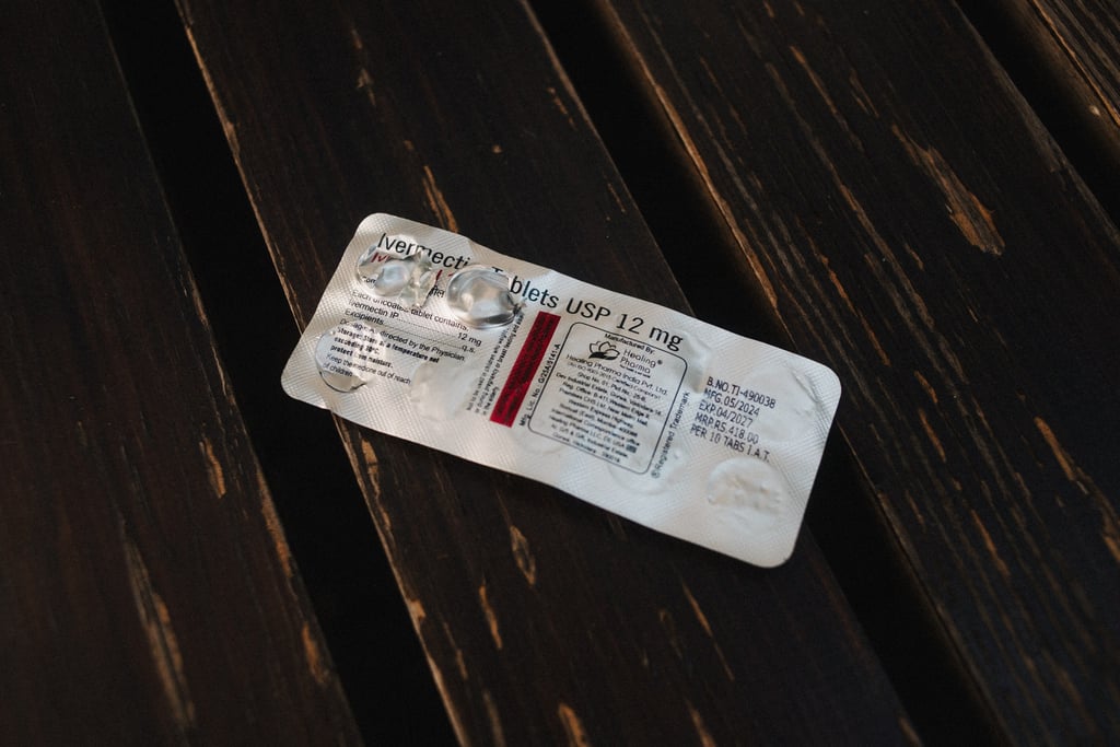 Brett med ivermectin-tabletter på 12 mg på et mørkt trebord, med to tabletter tatt ut.