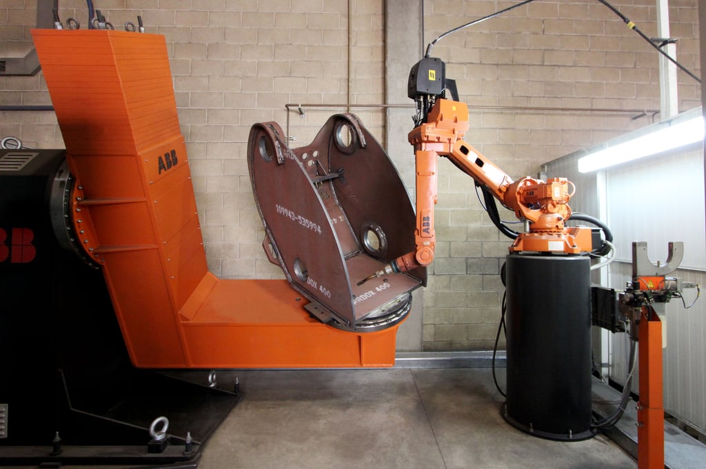 Industrirobot som sveiser på et samlebånd i en fabrikkhall