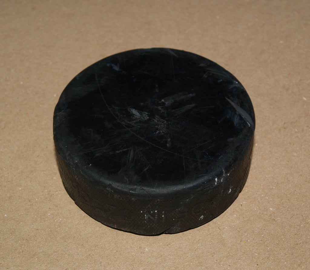 Ishockeypuck fotografert på hvit bakgrunn, brukt som størrelsessammenligning for OpenAI-enheten