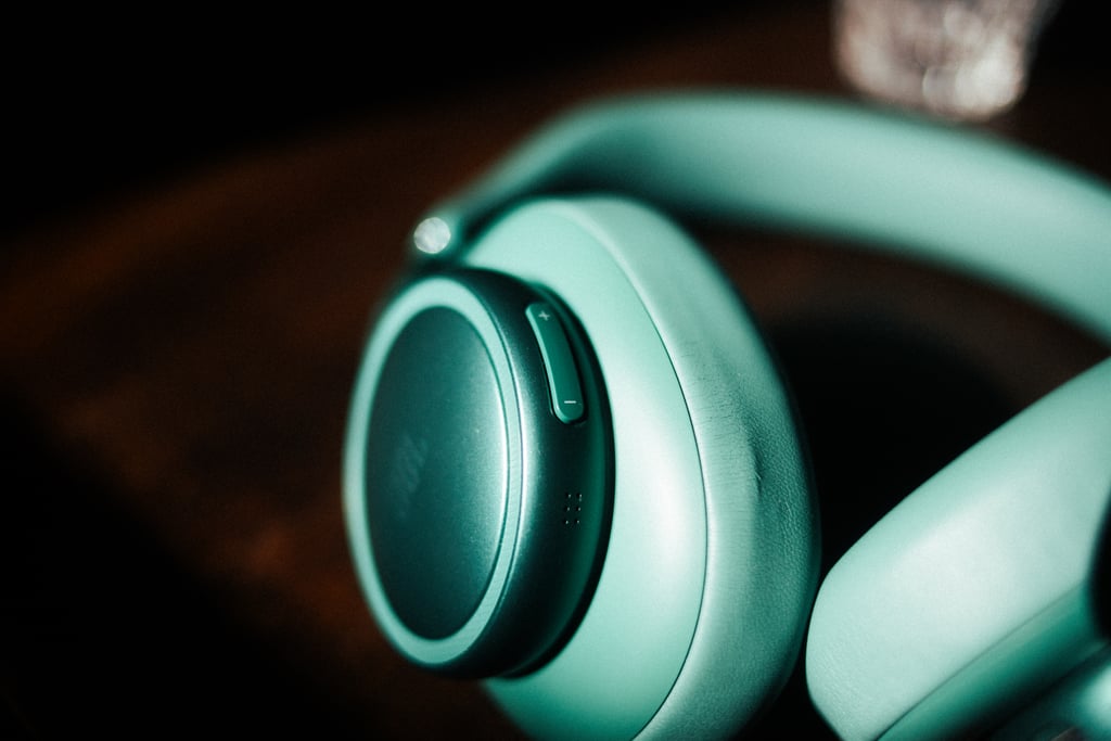Nærbilde av øreklokken på JBL Live 780NC der mikrofonhullene så vidt synes i kanten