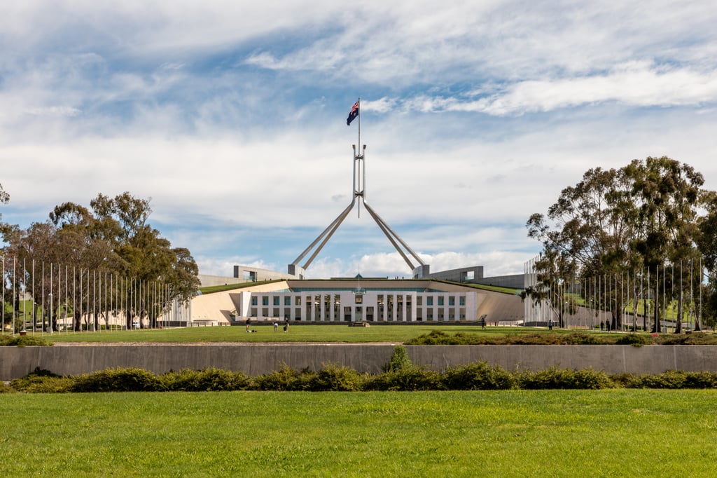 Australias parlamentsbygning i Canberra sett over gressbakken en klar dag