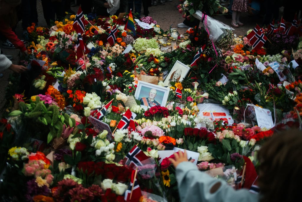 Blomsterhav med norske flagg og portretter av kong Harald på Slottsplassen