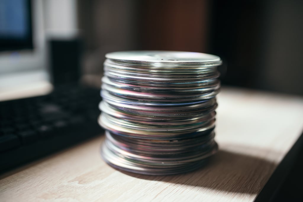 Stabel med CD-plater på et trebord ved siden av et datatastatur på et hjemmekontor