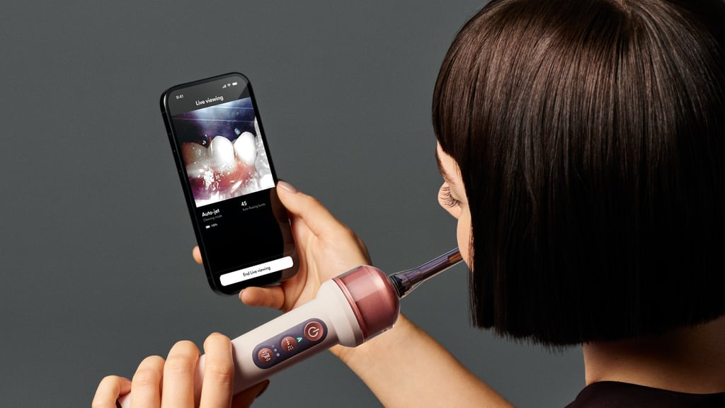 Kvinne pusser tennene med Dyson CameraJet mens mobilen viser bildet fra kameraet i munnen