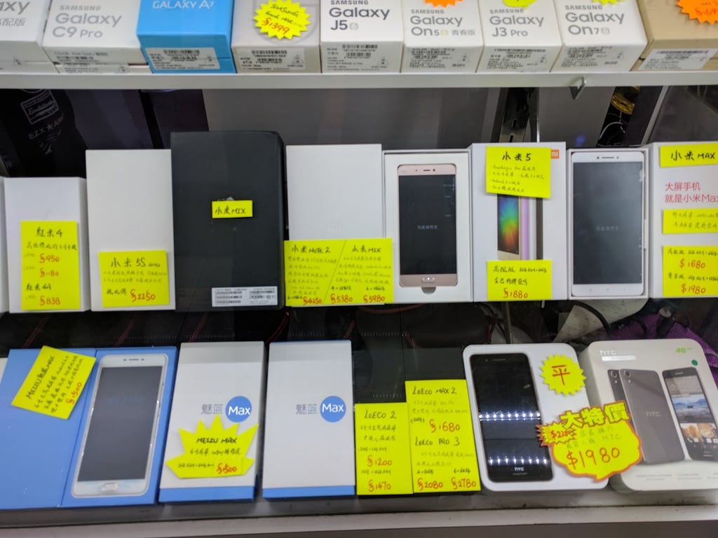 Butikkhylle i Hong Kong full av eldre mobiltelefoner i esker med gule prislapper
