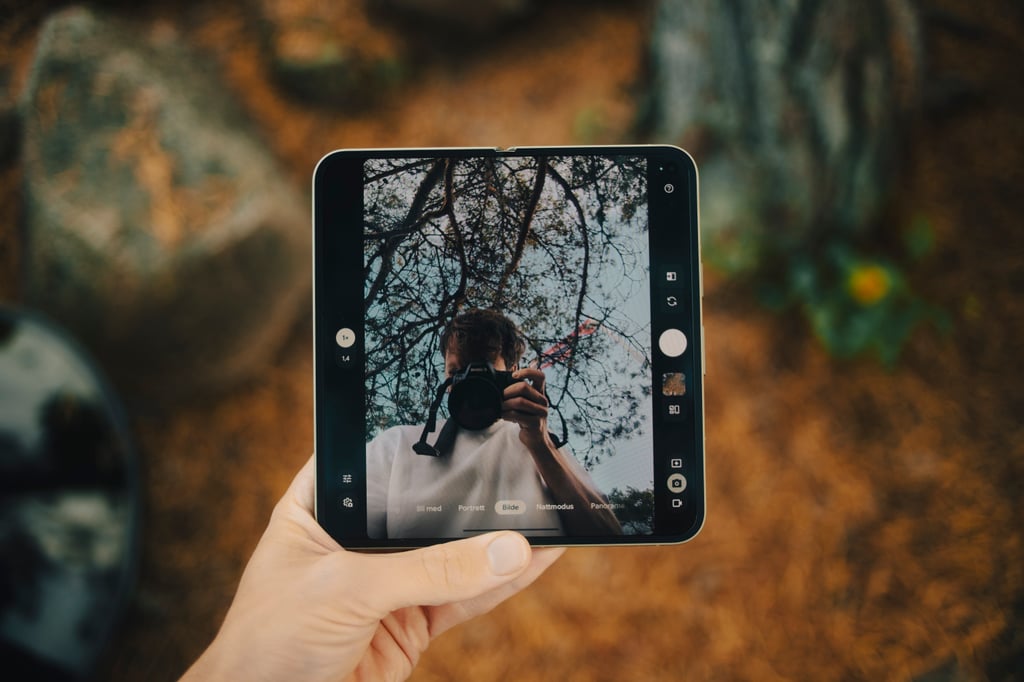 Google Pixel 11 Pro Fold i hånden med kamera-appen åpen og en person med kamera på skjermen