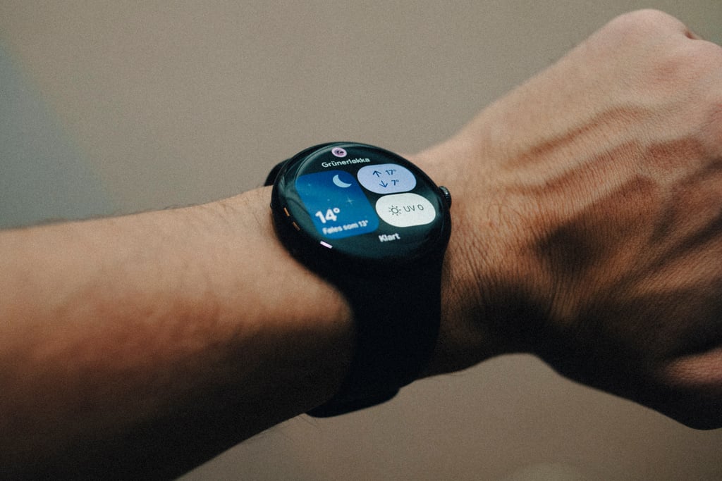 Pixel Watch 5 med sort reim på et håndledd, med værvisning på skjermen