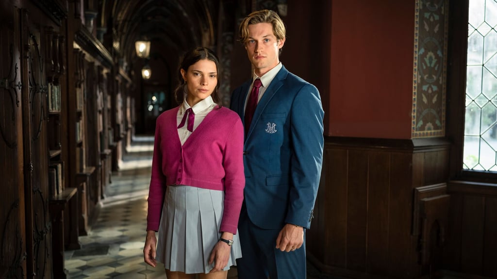 Hovedrolleinnehaverne i Maxton Hall i skoleuniform i en mørk korridor med treverk og blyglassvinduer