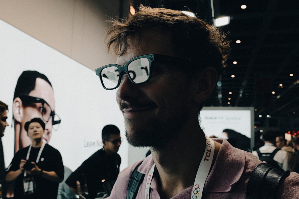 Mann med Rokid Glasses på i messehallen, tekst synlig i brilleglasset