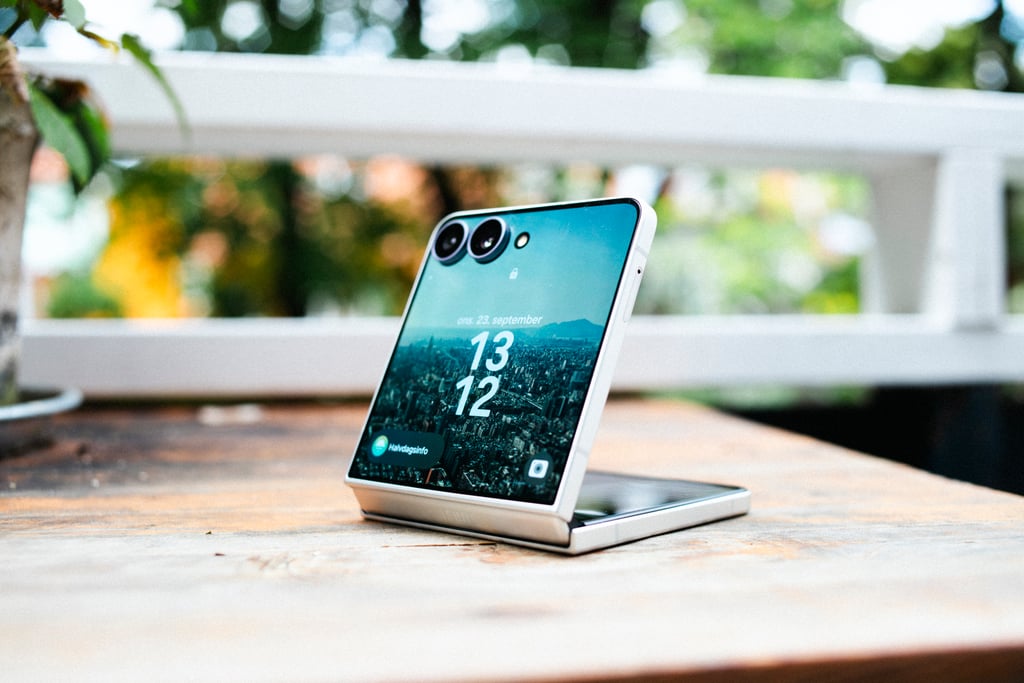 Samsung Galaxy Z Flip8 halvveis brettet opp på et utebord, med klokken på omslagsskjermen