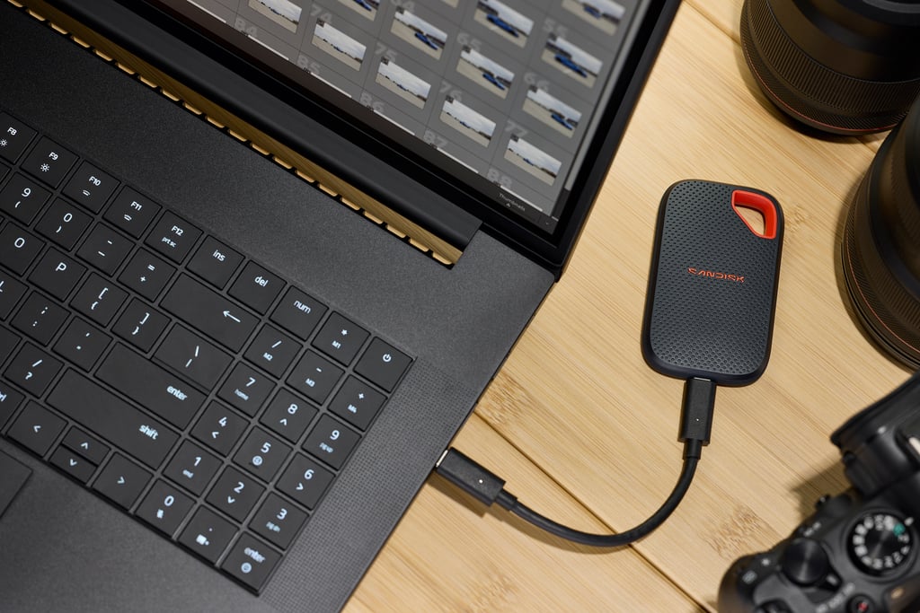 Sandisk Extreme Portable SSD koblet med kabel til en bærbar PC på et trebord