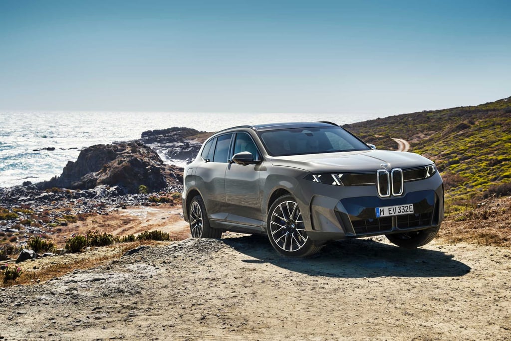 BMW iX5 60 xDrive parkert skrått forfra på en klippe ved havet