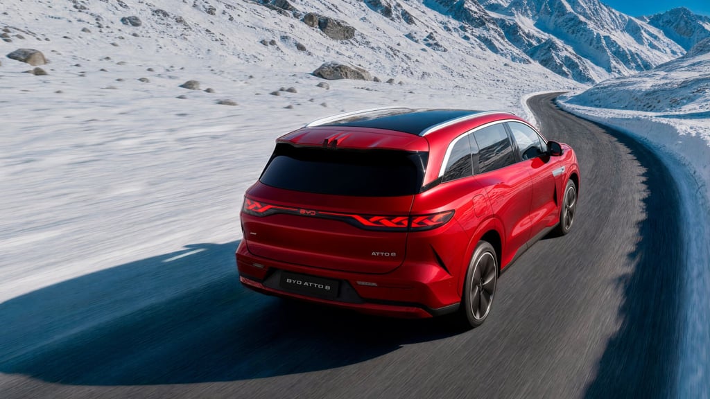 Rød BYD Atto 8 sett bakfra på en svingete fjellvei i snø, med lysstripe tvers over bakluken