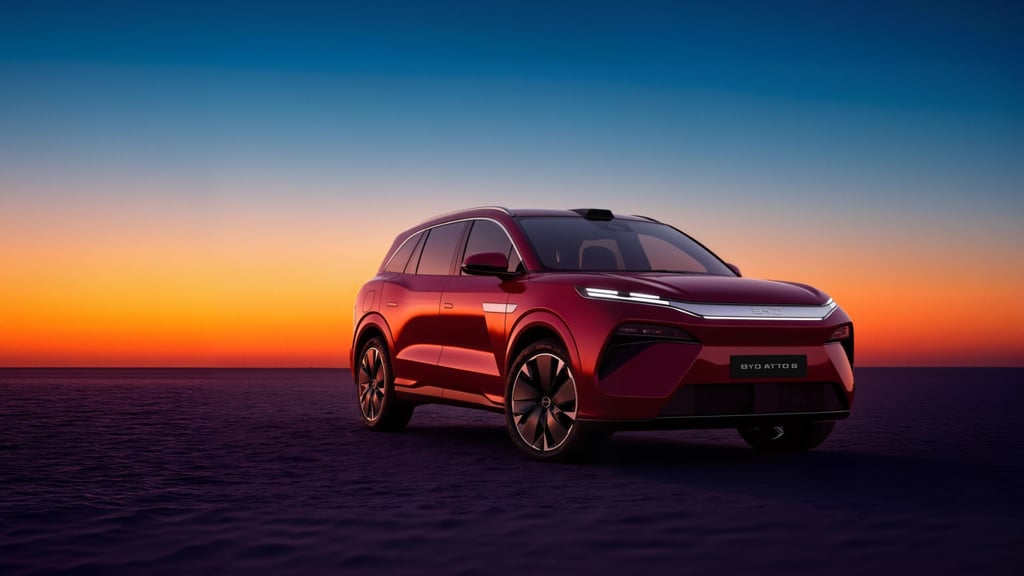 Rød BYD Atto 8 sett skrått forfra mot en oransje solnedgang