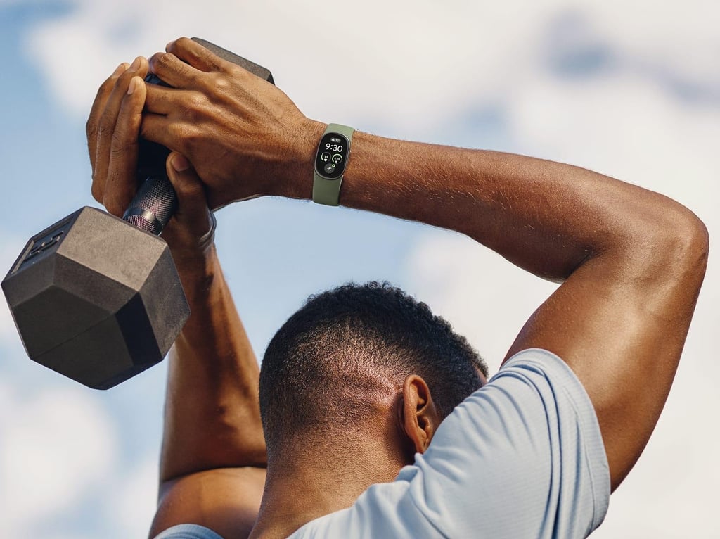 En mann løfter en manual bak hodet med et grønt Fitbit Edge på håndleddet