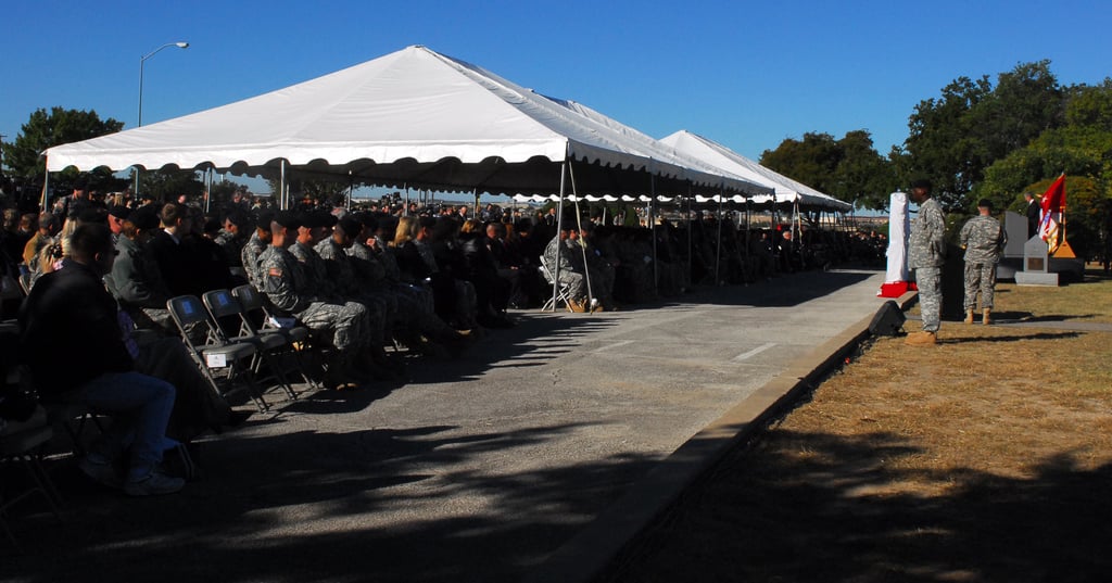 Soldater og pårørende sitter under hvite telt under en minneseremoni på Fort Hood