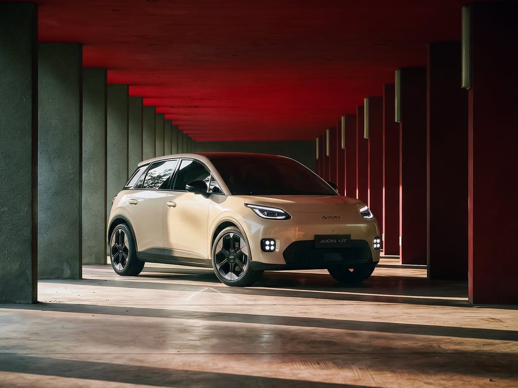 Beige GAC Aion UT parkert mellom røde betongsøyler