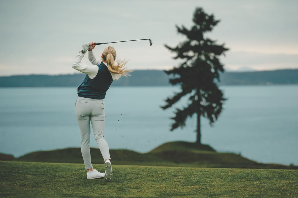 Golfspiller sett bakfra etter et slag, med sjø og et furutre i bakgrunnen