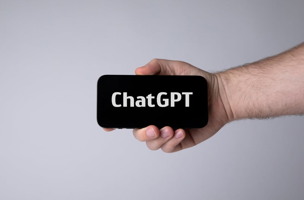 En hånd holder en mobiltelefon som viser ChatGPT på skjermen