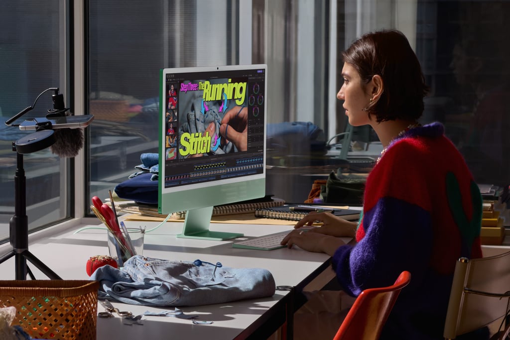 En kvinne redigerer video på en grønn iMac ved et vindu