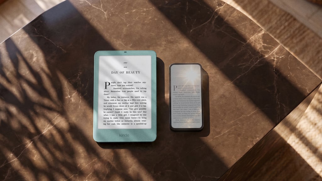 Grønn Kindle Paperwhite og en mobiltelefon ligger side om side på et brunt marmorbord i sollys