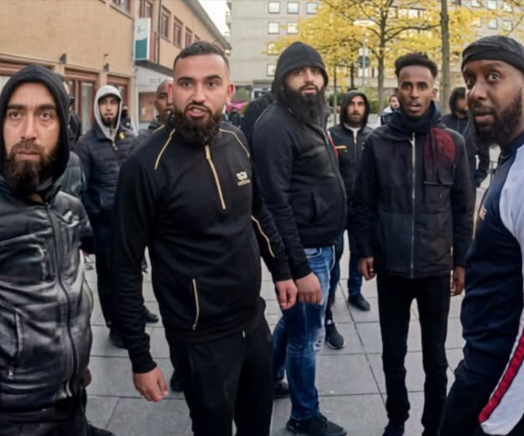 En gruppe unge menn i mørke jakker står samlet i en gate