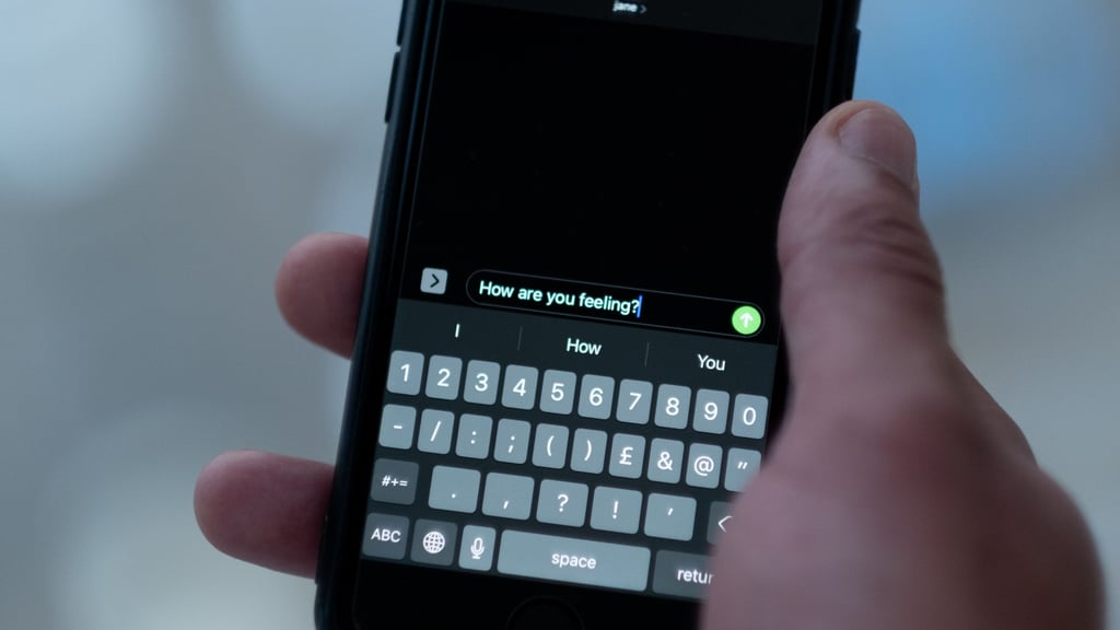 Hånd som holder en smarttelefon og skriver en tekstmelding innendørs