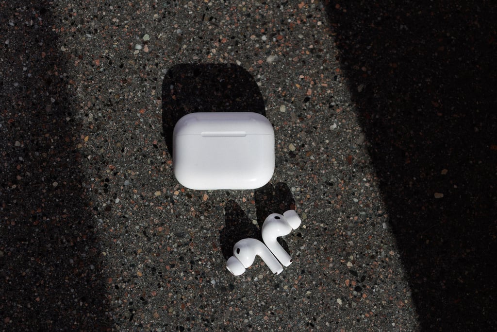 AirPods Pro 3-etui og begge proppene på grå asfalt