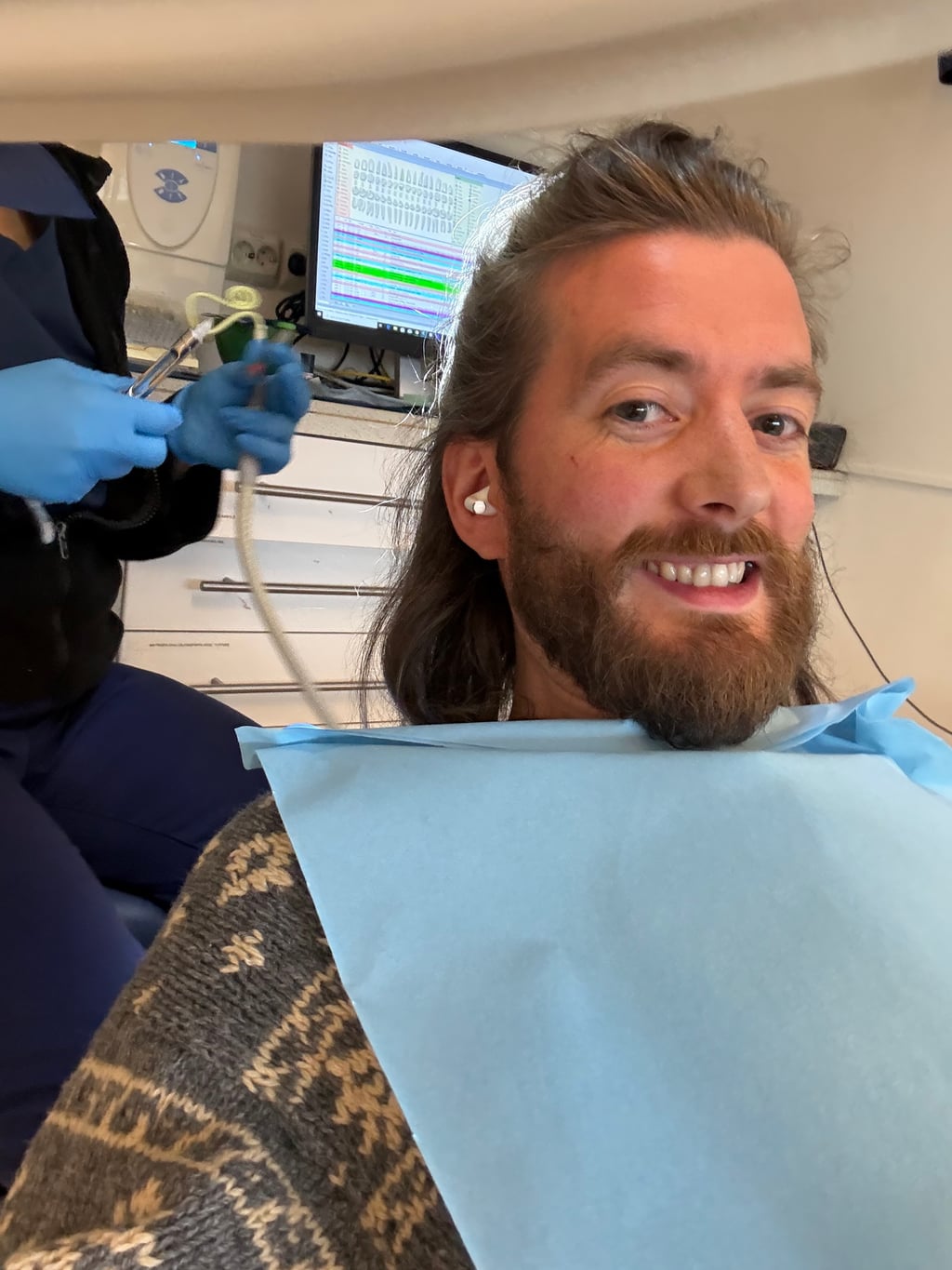 Julian med AirPod i øret i tannlegestolen, blå hakelapp