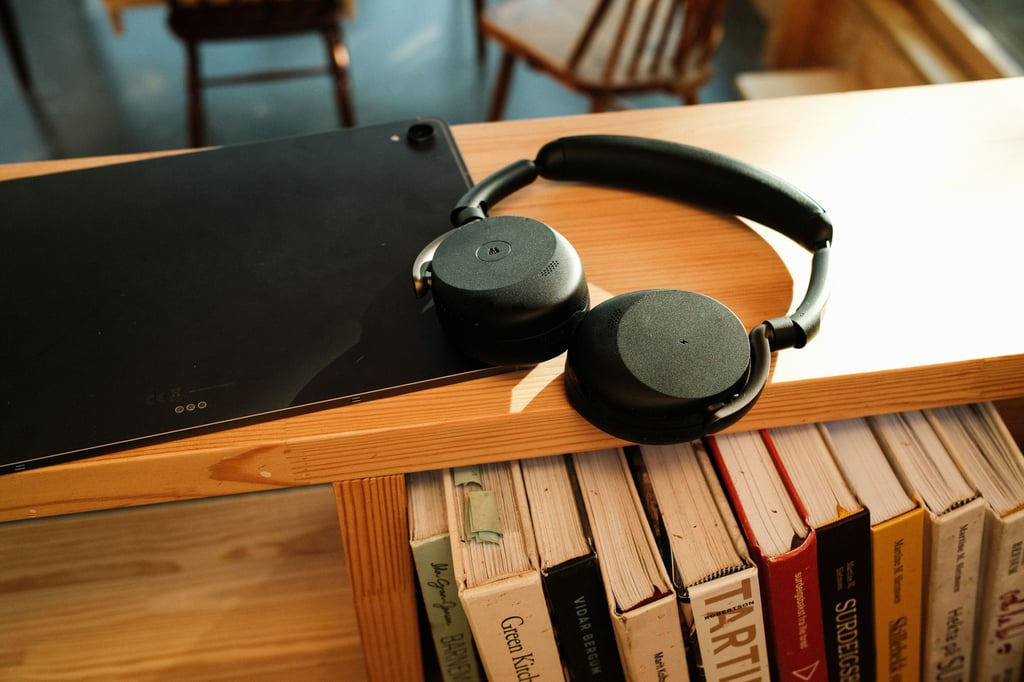 Jabra Evolve3 65 Flex lent mot et Galaxy Tab-nettbrett over en bokhylle