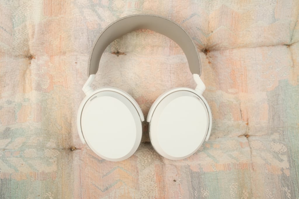 Sennheiser Momentum 5 i kremhvitt, liggende på et teppe