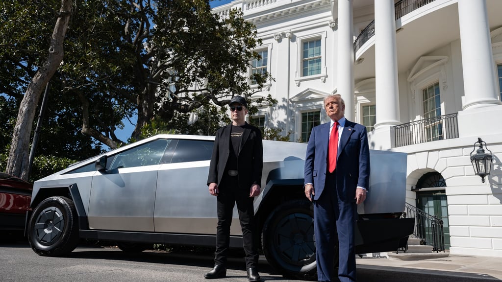 Elon Musk i svart og Donald Trump i dress og rødt slips står foran en sølvfarget Cybertruck utenfor Det hvite hus