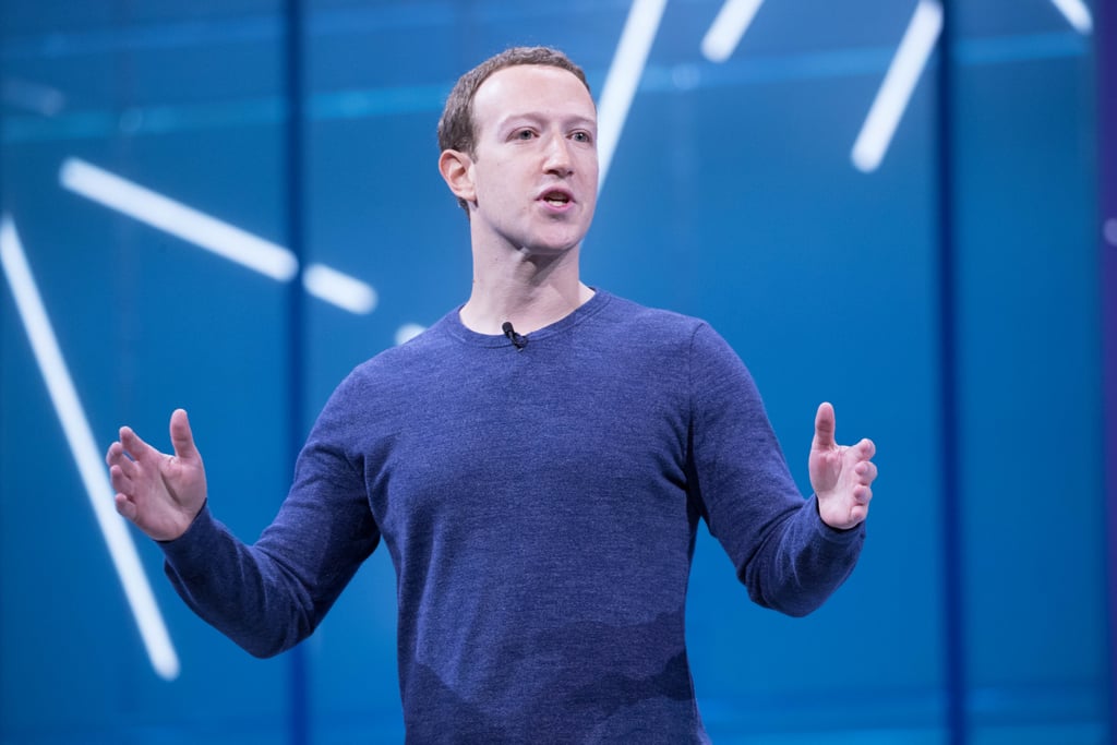 Mark Zuckerberg på scenen under F8 med utstrakte hender mot blå bakgrunn