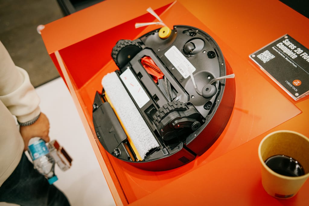 Undersiden av robotstøvsugeren Saros 20 Flow Complete med hvit rullemopp, utstilt på oransje bord på Roborocks stand