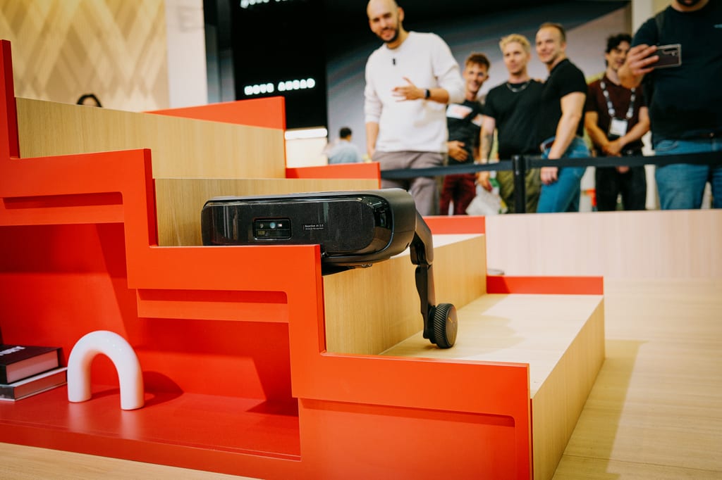 Roboten Saros Rover klatrer en trapp i tre og oransje på Roborocks stand mens publikum ser på