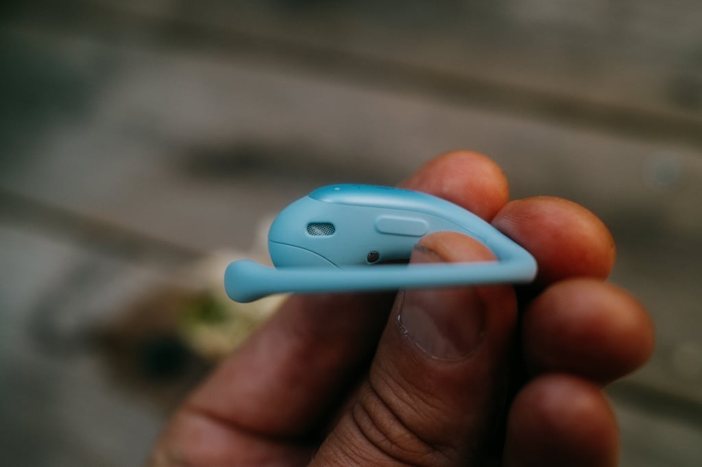 En OpenFit Air 2-propp i hånda, knappen på siden synlig
