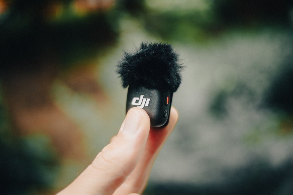 DJI Mic 3-mikrofon med svart vindhette holdt mellom to fingre