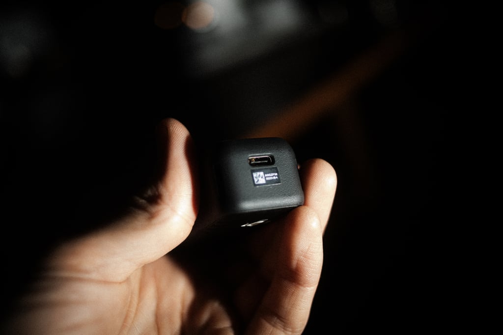 Undersiden av DJI Osmo Pocket 4 med USB-C-kontakt holdt mellom to fingre