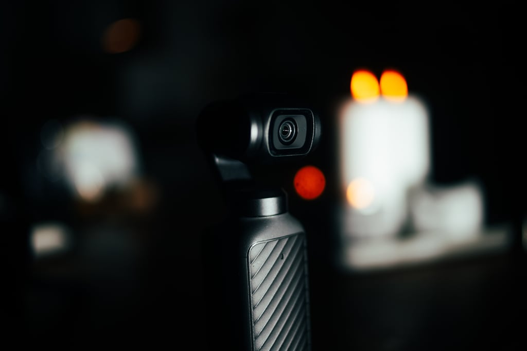Gimbalhodet og objektivet på DJI Osmo Pocket 4 mot et mørkt rom med levende lys
