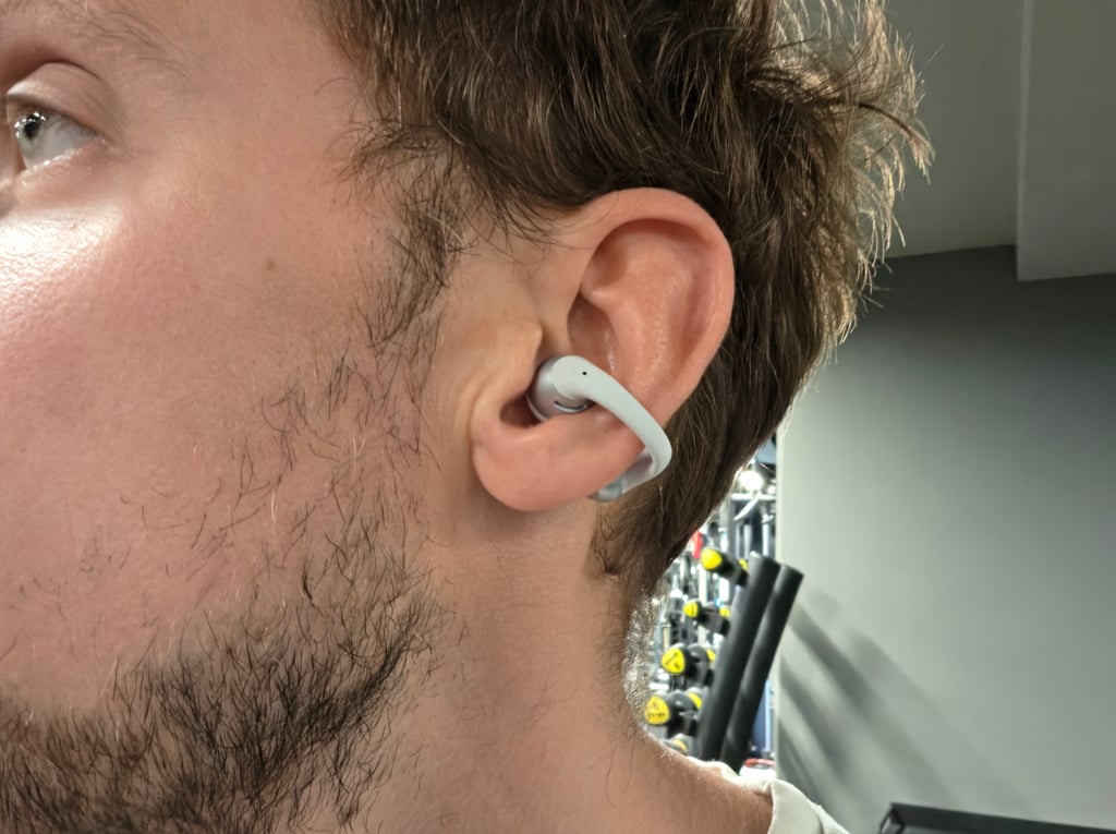 Shokz OpenDots 2 på øret under trening, med vektstativ i bakgrunnen