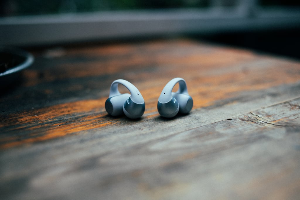 Begge Shokz OpenDots 2-proppene står oppreist ved siden av hverandre på et trebord